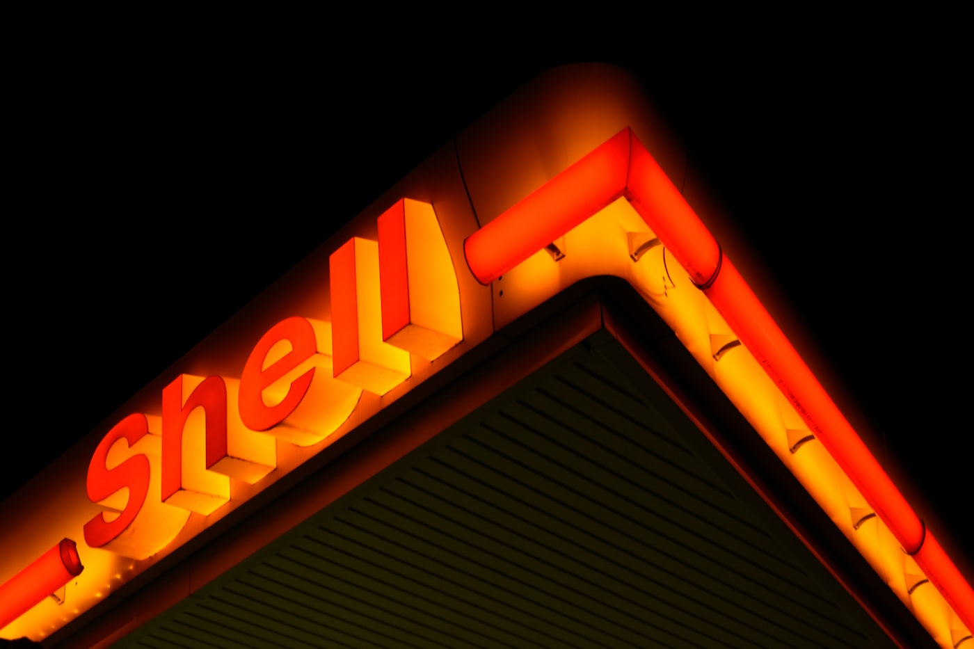 Illuminated sign on the corner of a service station canopy at night