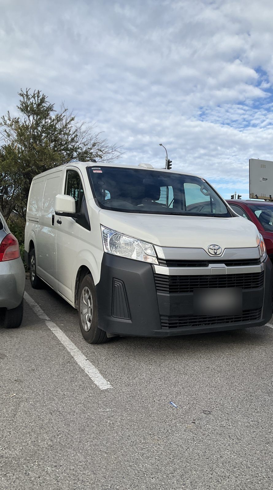 White Toyota Hiace van parked in a car park under a cloudy sky, Hallett Cove