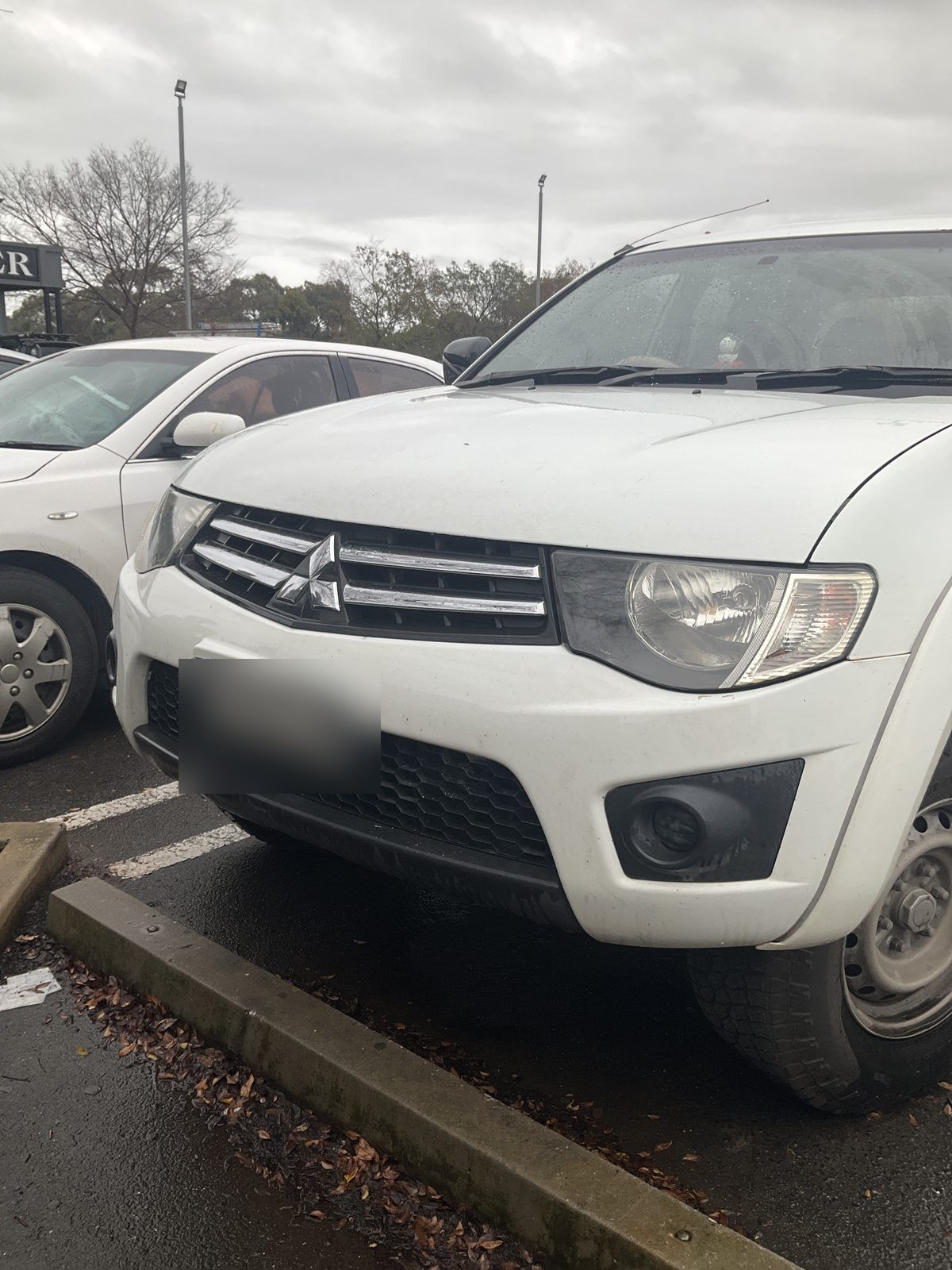 White Mitsubishi Triton parked in a car park under an overcast sky, Angle Vale