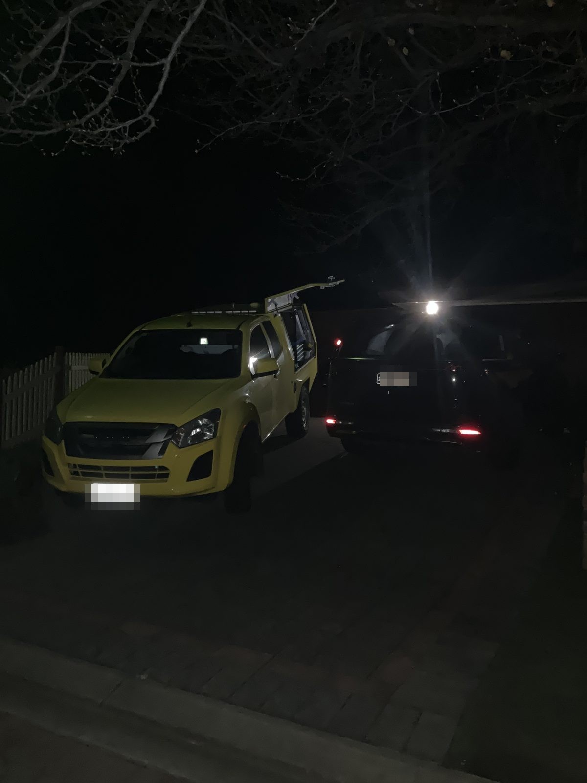 Yellow service ute beside a customer's vehicle in a driveway at night, Greenwith