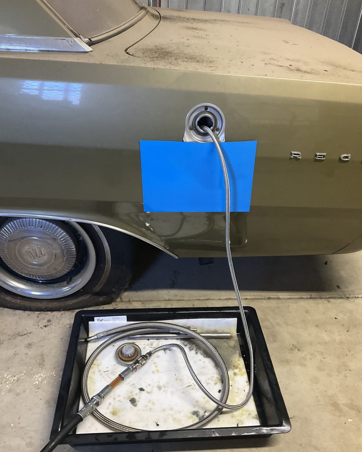 Drain hose in the fuel filler of a vintage Valiant, running to a tray on the shed floor